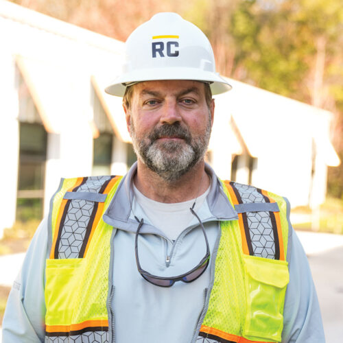 Construction worker in RC hard hat and safety vest outdoors.