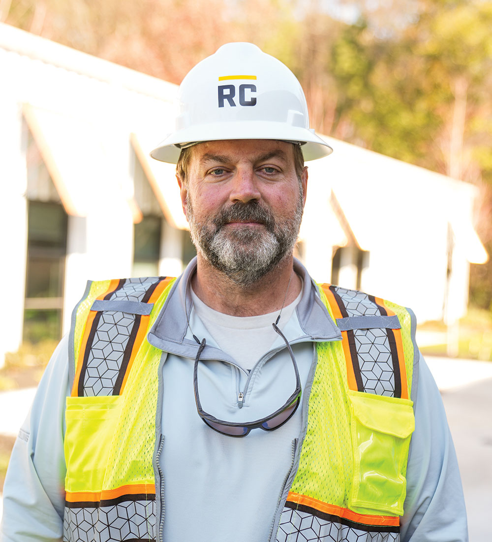 Construction worker in RC hard hat and safety vest outdoors.