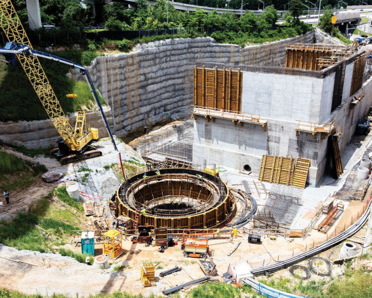 Construction site with concrete structure, circular foundation, crane, equipment.