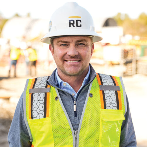 Worker in white RC hard hat and safety vest at site.