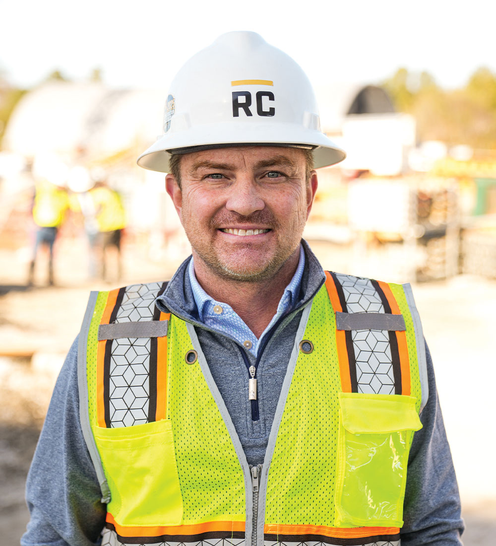 Worker in white RC hard hat and safety vest at site.