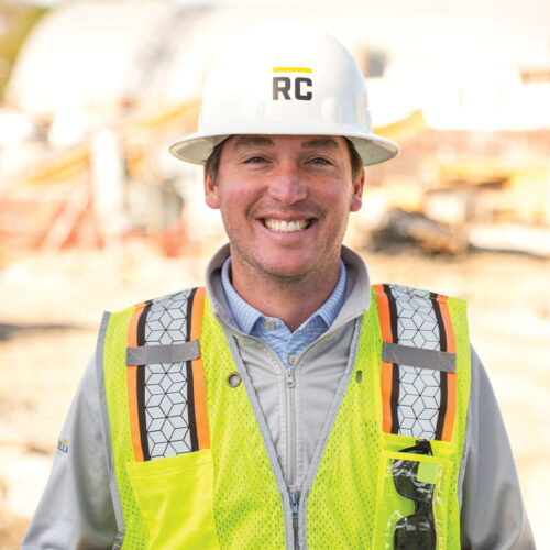 Smiling construction worker in hard hat and safety vest.