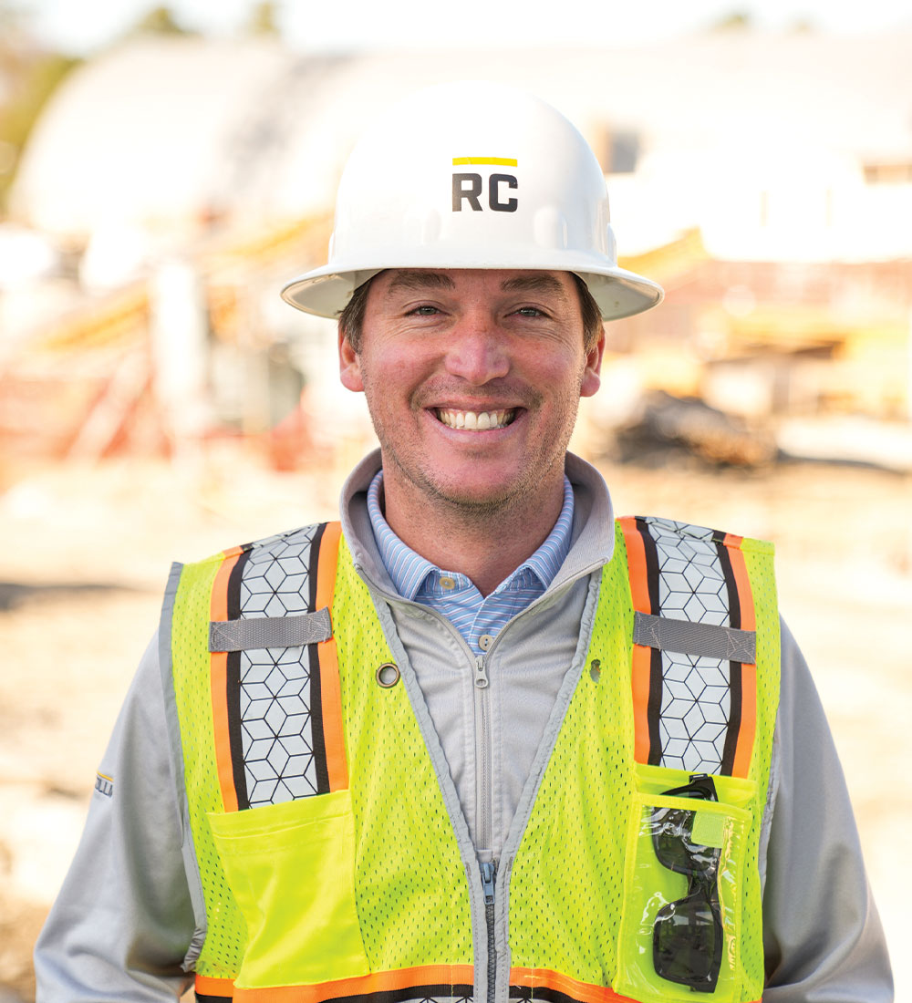 Smiling construction worker in hard hat and safety vest.