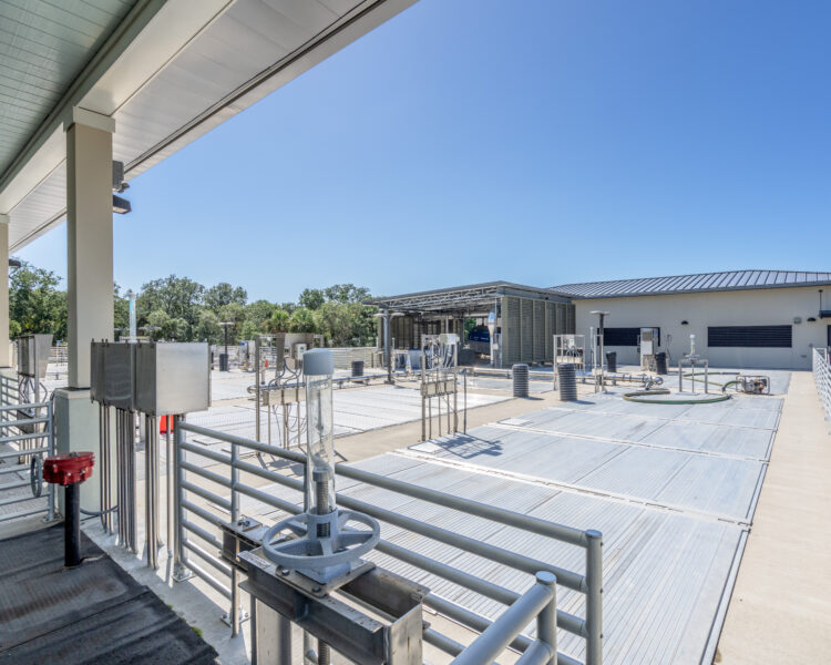 Industrial water treatment plant with railings, valves, blue sky.