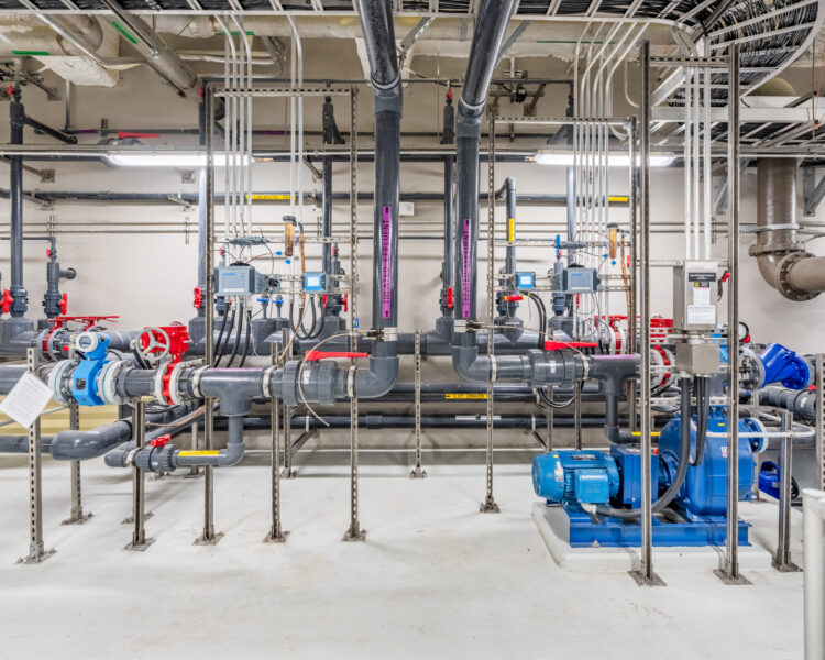 Industrial mechanical room with pipes, valves, controls, and pumps.