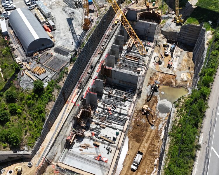 Aerial view of construction site with cranes by a highway.