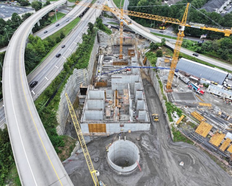 Aerial view: highway interchange and nearby construction with cranes.