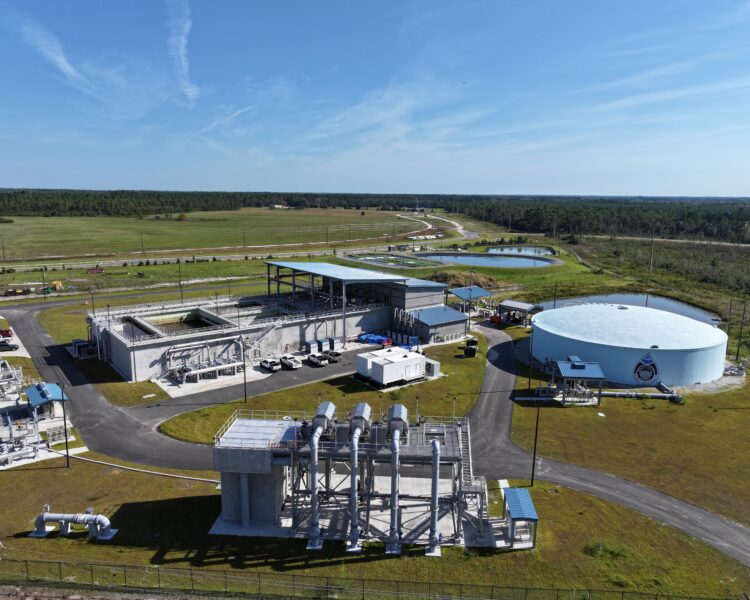Aerial view of water treatment plant, tanks, and grassy fields.