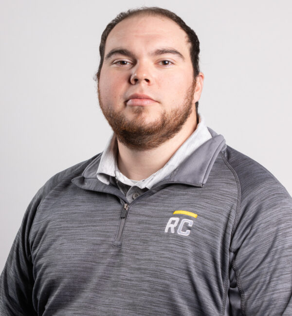 Man with short hair and beard in gray pullover, plain background.