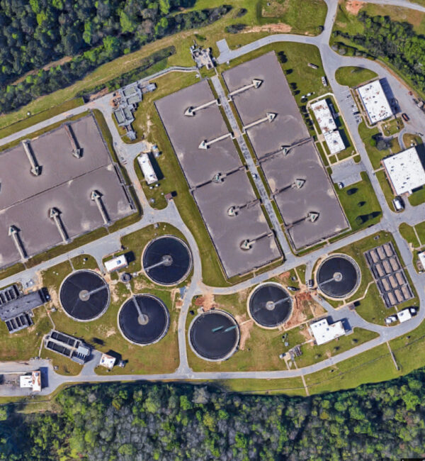 Aerial view of a wastewater plant with various tanks and buildings.