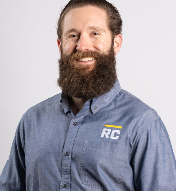 Hombre con barba que lleva una camiseta azul del RC y sonríe a la cámara.