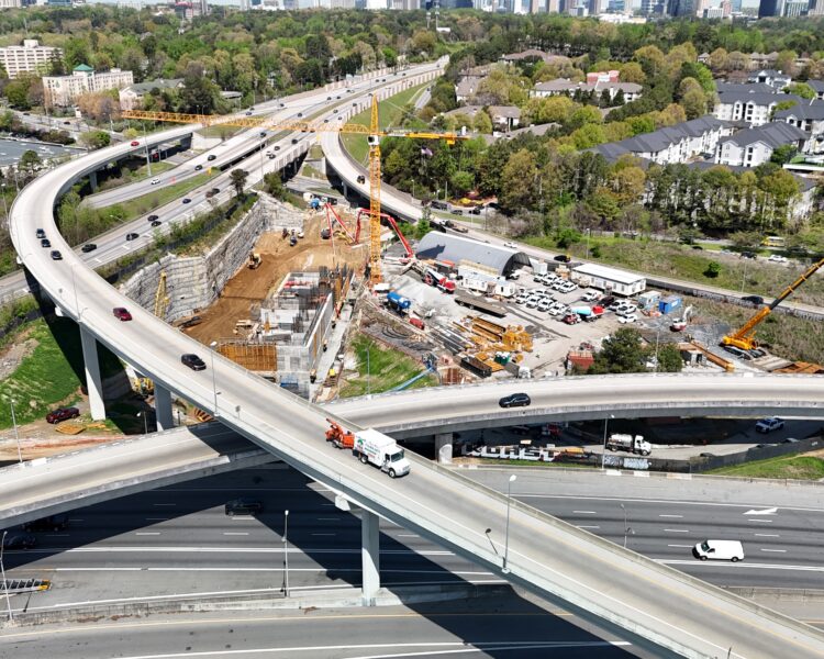 Aerial shot of highway interchange under construction amid trees.