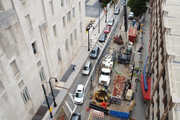 Una calle de la ciudad vista desde arriba, con obras, vehículos y conos.