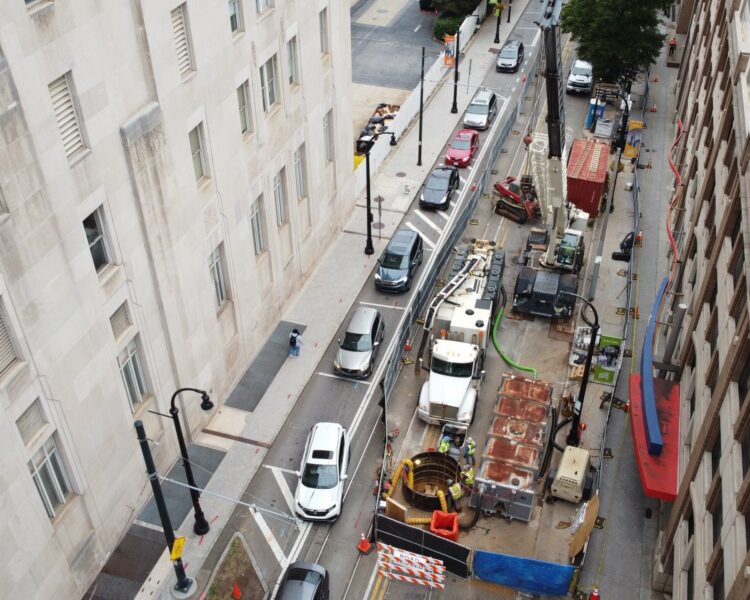 Una calle de la ciudad vista desde arriba, con obras, vehículos y conos.