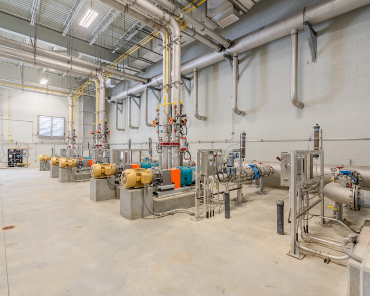 Filas de grandes bombas, tuberías y sistemas de control en una instalación industrial.