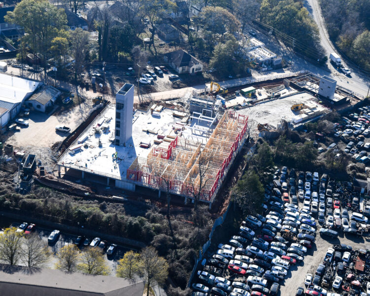 Aerial view of building under construction by filled parking lot.
