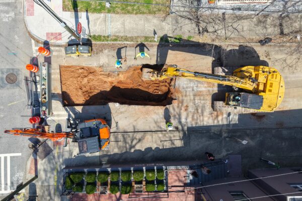 Vista aérea de dos excavadoras y unos trabajadores excavando una calle.