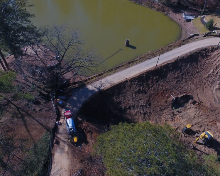 Vista aérea: obra junto a un estanque con vehículos y maquinaria.