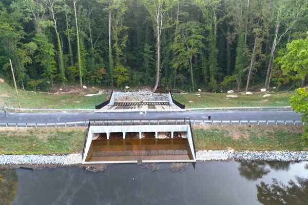 Un puente con calzada y barreras de seguridad cruza el río en medio de la vegetación.