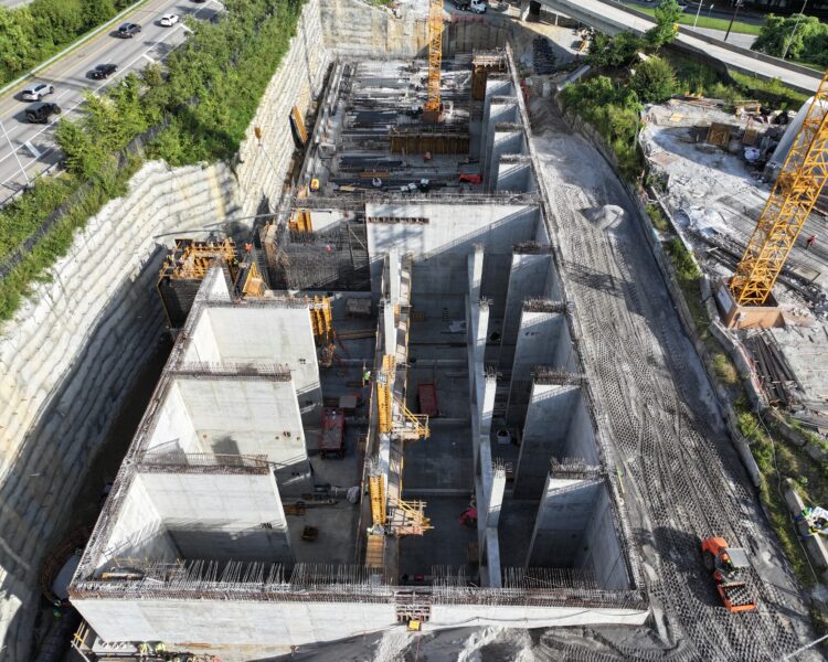 Aerial view of construction site with cranes and concrete walls.