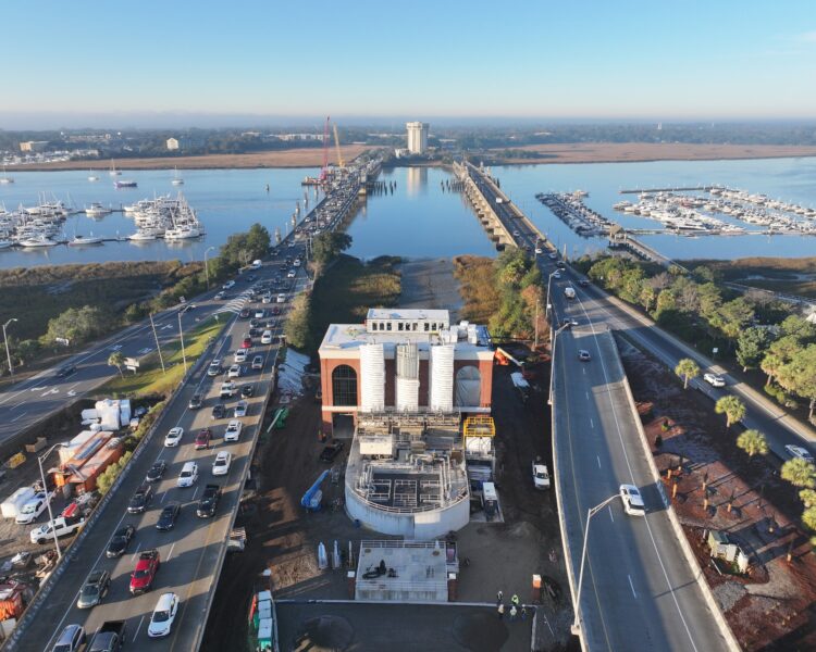 Bridge under construction over water, with cars and marinas.