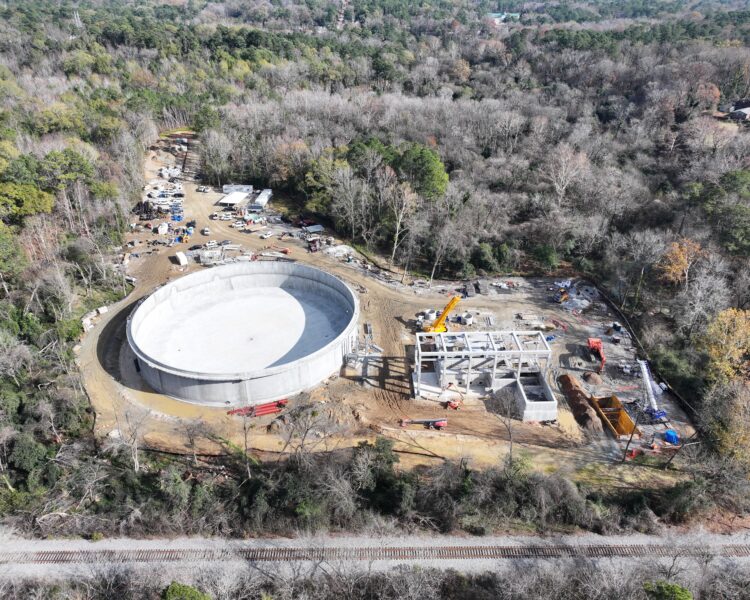 Aerial view: circular structure, foundations, trees, construction gear.