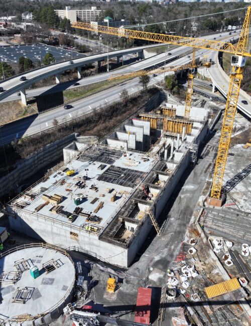 Aerial view of cranes and concrete at a highway construction site.
