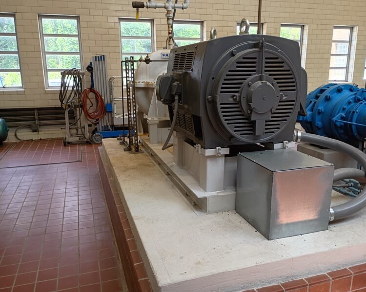Industrial motor and pump on a concrete platform in utility room.