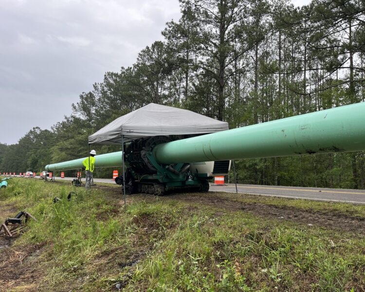 Instalación de una tubería ecológica por carretera, con trabajadores y maquinaria de construcción en las inmediaciones.