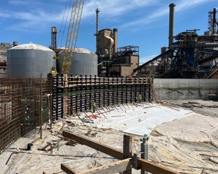 Construction site with workers, crane, rebar, and silos.