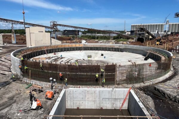 Los trabajadores montan barras de refuerzo en una gran cimentación circular en la obra.