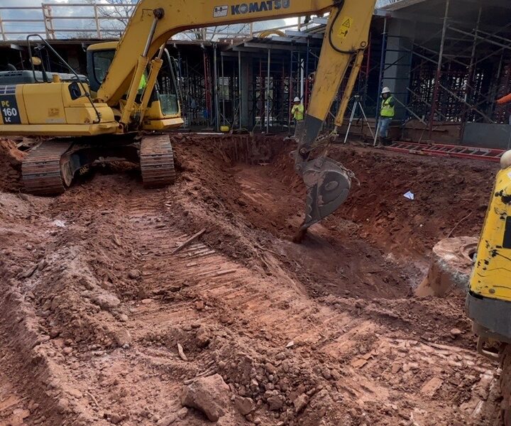 Una excavadora Komatsu amarilla excava una zanja en una obra.