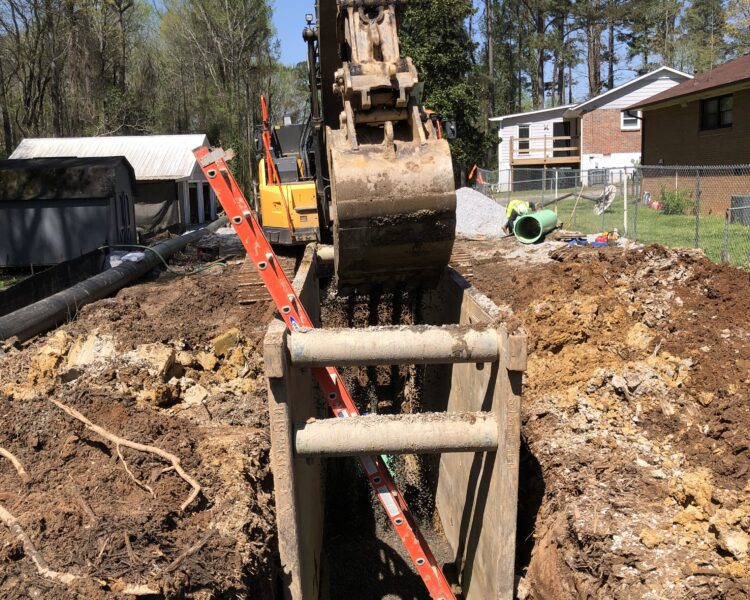 Excavator digs trench with green pipe and red ladder nearby.