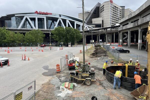 Unos trabajadores instalan la infraestructura en el aparcamiento; al fondo se ve el State Farm Arena.