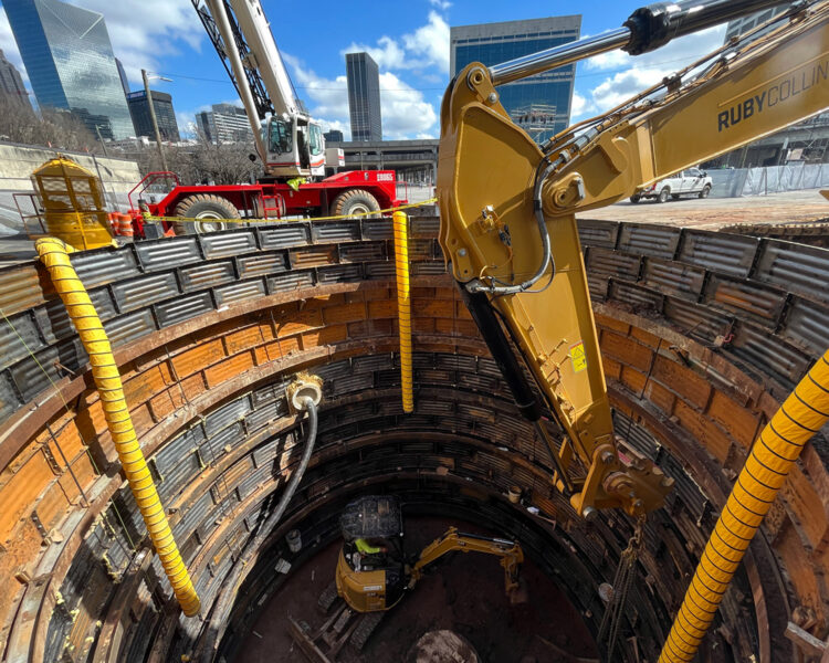 Las excavadoras operan dentro y sobre un pozo de construcción circular y profundo.