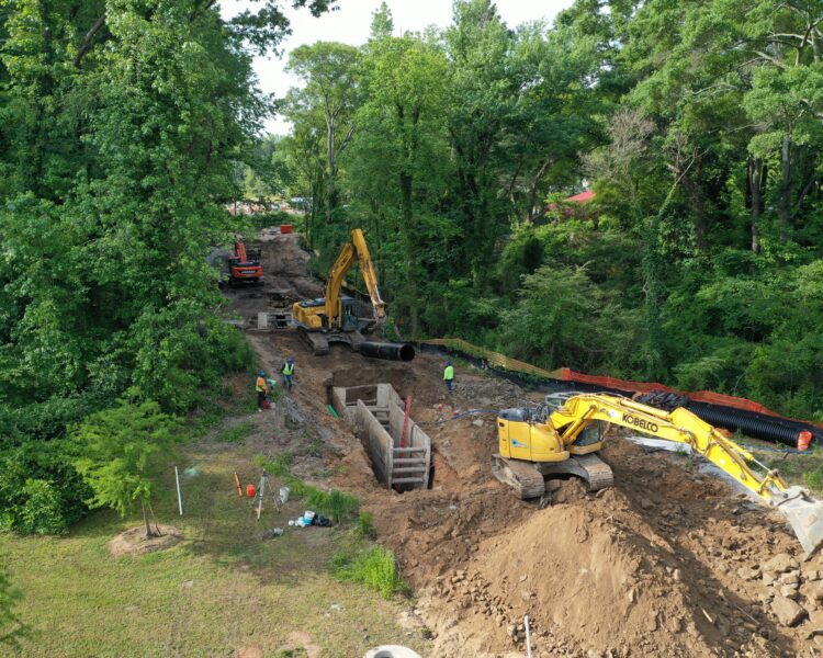 Excavadoras y trabajadores en una obra forestal con tuberías.