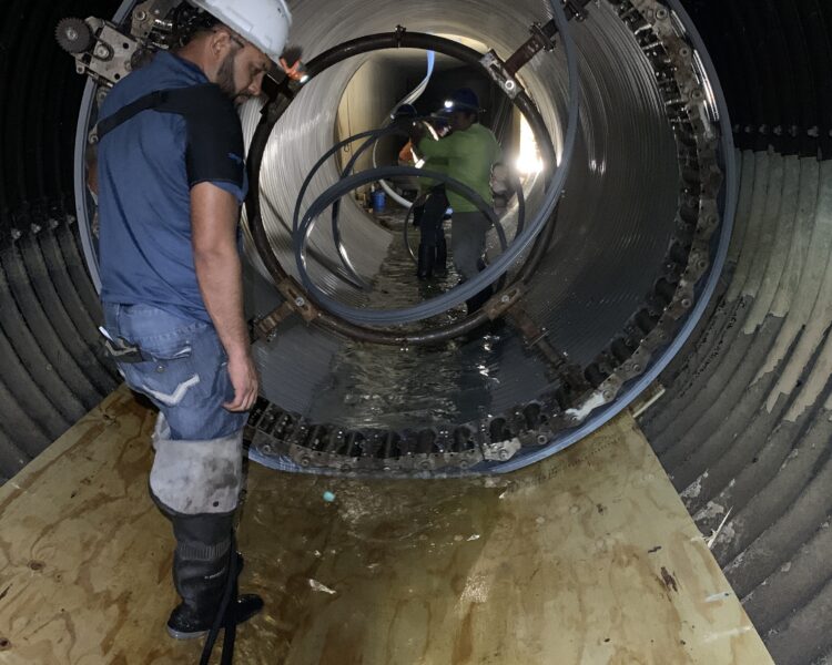 Dos trabajadores inspeccionan los cables en el interior de un gran cilindro metálico.