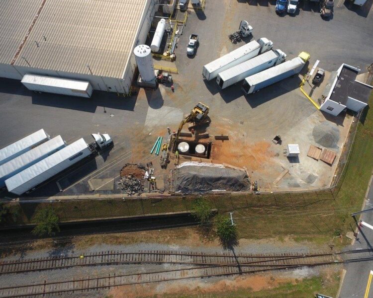 Aerial view of trucks and workers excavating tanks at facility.