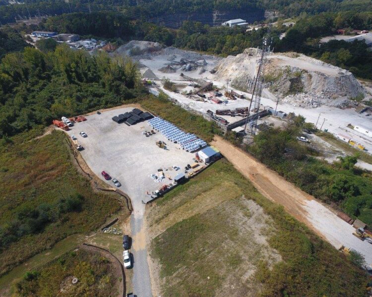 Aerial view: construction site, vehicles, materials, quarry nearby.