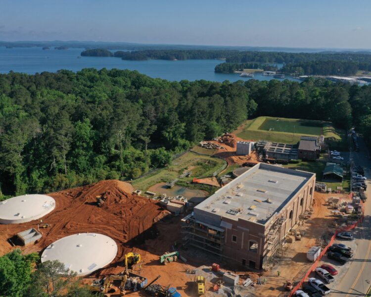 Vista aérea: dos estructuras circulares, un edificio rectangular, árboles, un lago.