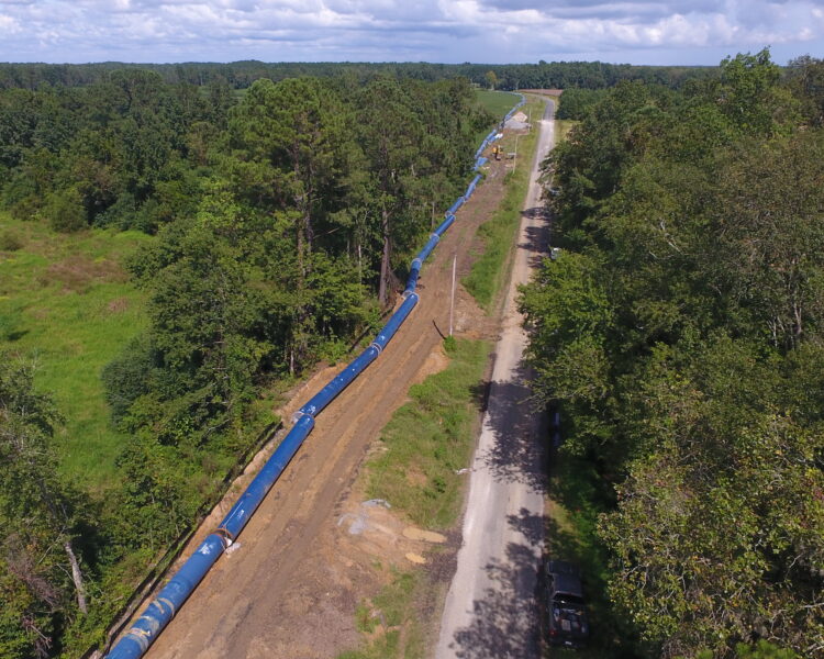 Se está construyendo un gasoducto junto a un camino de tierra en un bosque cubierto de hierba.