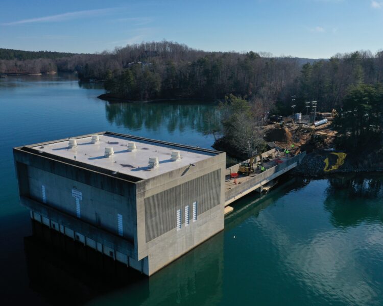 Concrete water intake facility in lake, connected to forest.