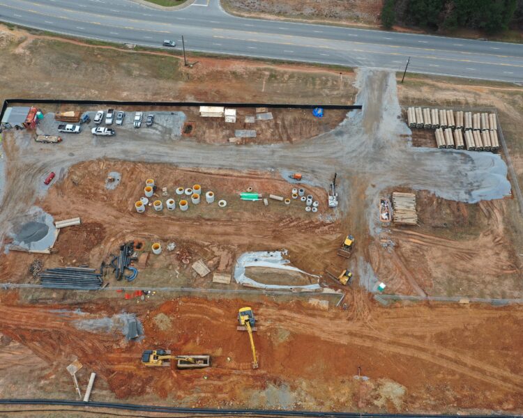 Aerial view of construction site with machines, materials, and vehicles.