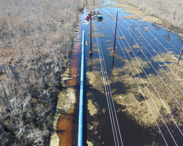 Las tuberías y las líneas eléctricas atraviesan bosques inundados; se observan obras de construcción.