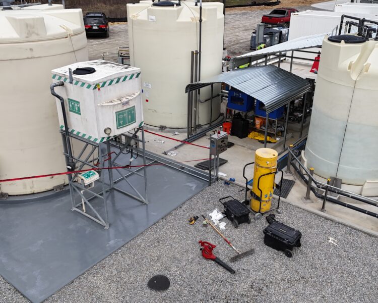 Depósitos y equipos industriales al aire libre sobre grava, con tuberías.
