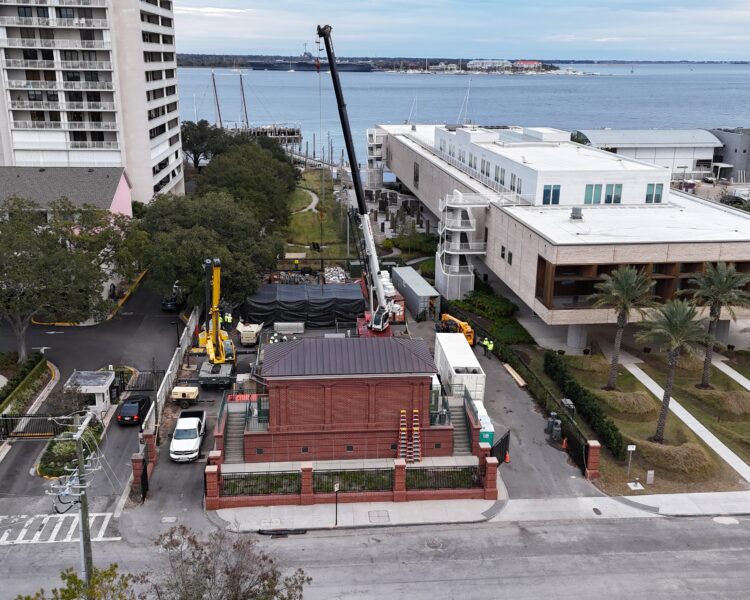 Active construction site with cranes, trucks, and workers near water.