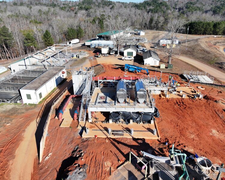 Aerial view of water treatment site with equipment and forest.