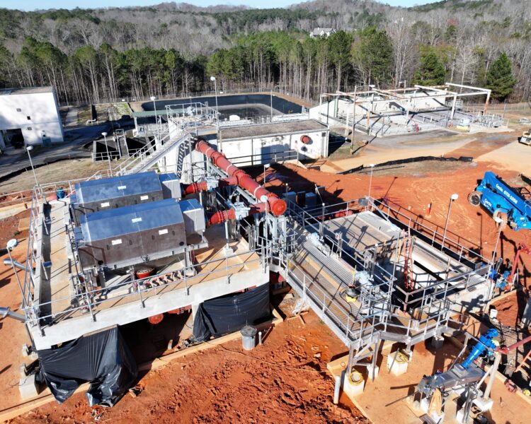 Aerial view of facility construction with metal frames and red soil.