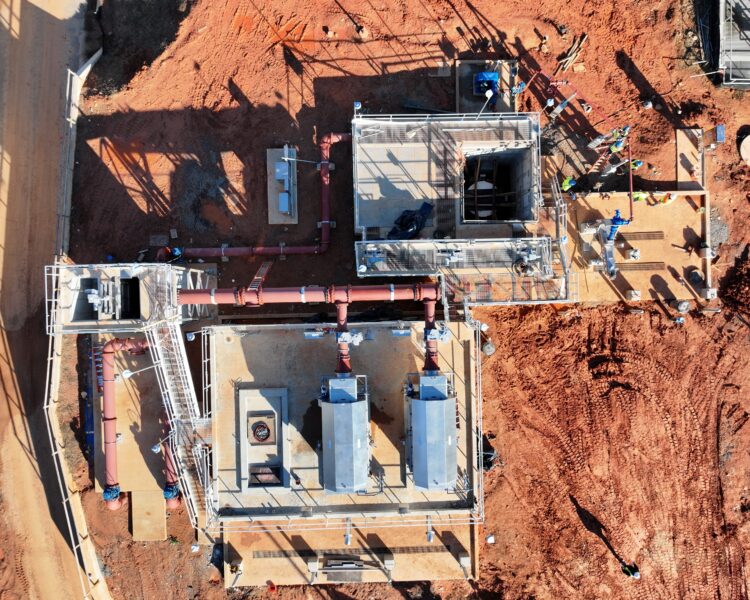 Aerial view of industrial site with structures, pipes, and workers.