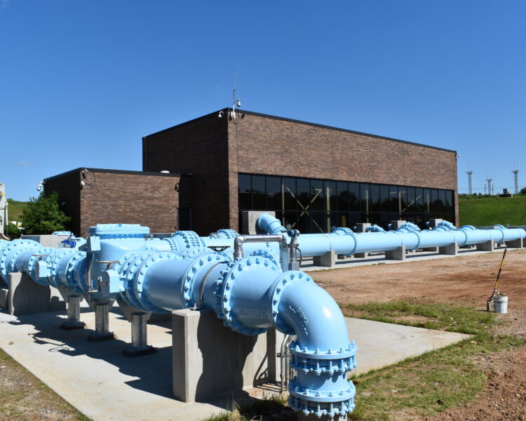 Edificio industrial de ladrillo con grandes tuberías y válvulas azules en el exterior.
